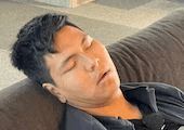 a young man is sleeping on a couch with his eyes closed .