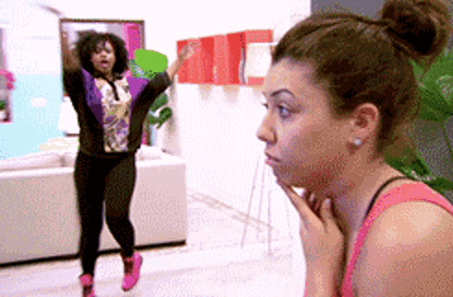 a woman in a pink tank top is standing next to another woman in a purple jacket