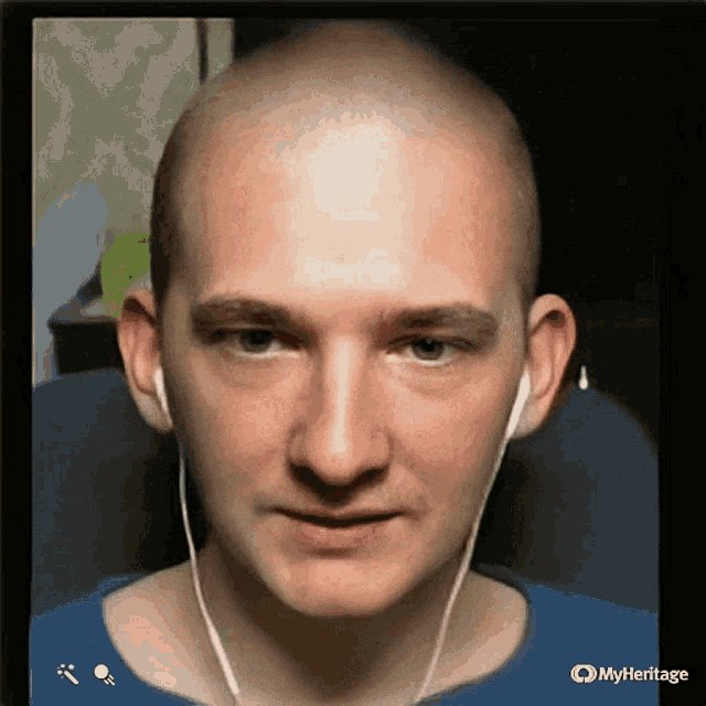 a bald man wearing ear buds and a blue shirt with myheritage written on the bottom right