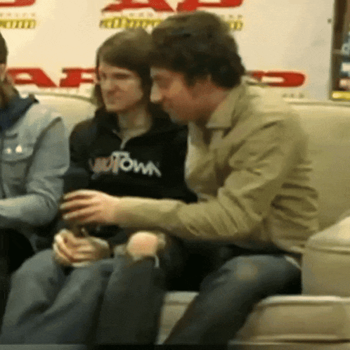 a group of people sitting on a couch one of whom is wearing a sweatshirt that says ' downtown ' on it