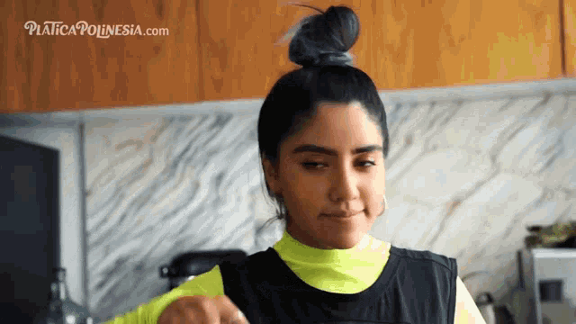 a woman in a kitchen with a bun and the website platecapolynesia.com in the background