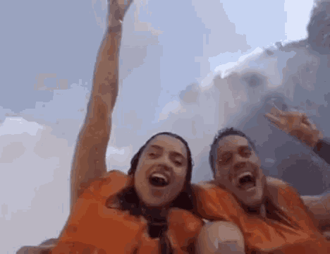 a man and a woman in orange life jackets are screaming in the water