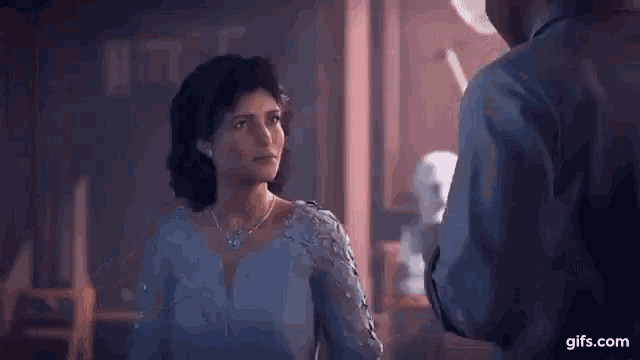 a woman in a blue dress is standing in a room .