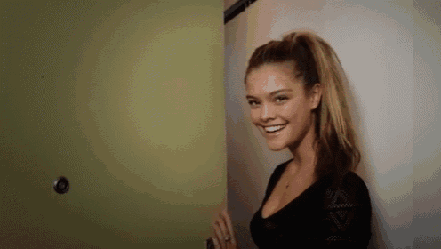 a woman is smiling while standing next to a door .