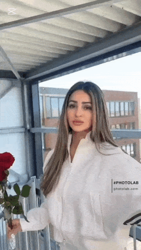 a woman in a white jacket is holding a bouquet of roses .