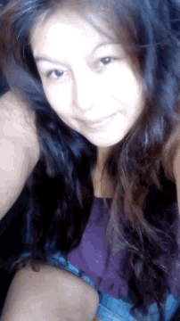 a woman in a purple tank top and blue shorts smiles