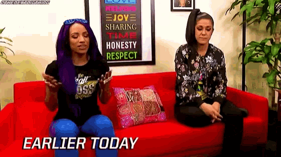two women are sitting on a red couch with the words earlier today written on the bottom .