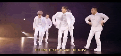 a group of men are dancing on a stage with the words `` the one that 's heard the most '' written above them .
