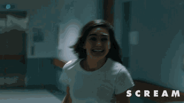a woman in a white shirt is running in a hallway with the word scream written above her