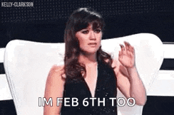 a woman in a black dress is sitting in a chair with her hand up and says `` im feb 6th too '' .