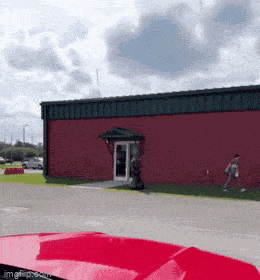 a red car is parked outside of a red building