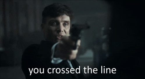 a man in a suit is pointing a gun at the camera and says you crossed the line .