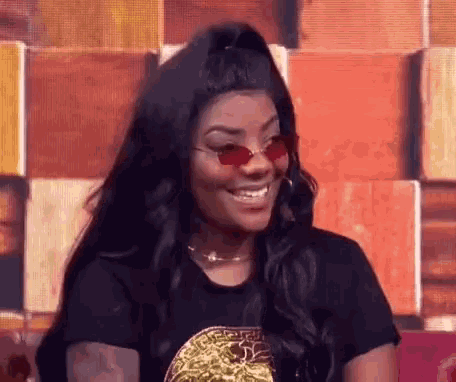 a woman wearing sunglasses and a black t-shirt is smiling .