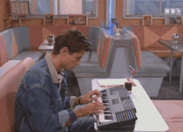 a man is sitting at a table playing a keyboard
