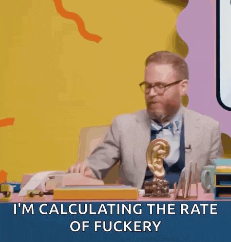 a man in a suit and bow tie is sitting at a desk and calculating the rate of fuckery .