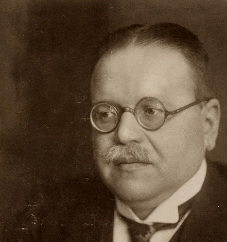 a man with glasses and a mustache is wearing a suit
