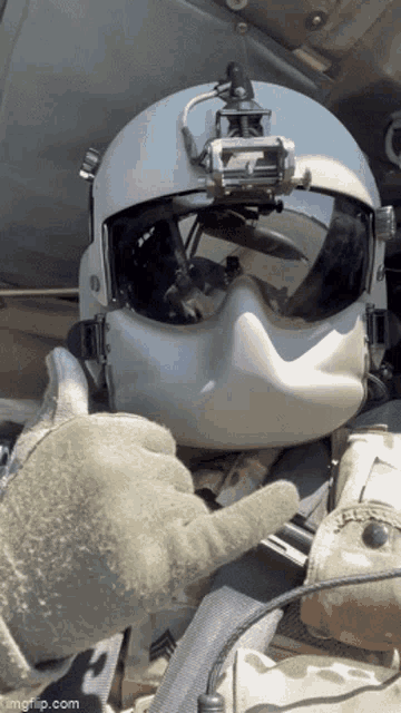 a soldier wearing a helmet and goggles is giving a thumbs up