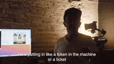 a man stands in front of a computer and says he 's putting in like a token in the machine