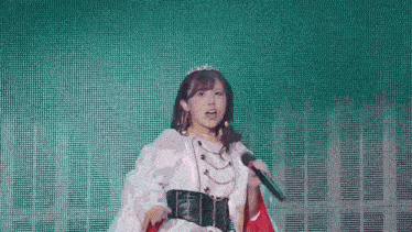 a woman in a crown is singing into a microphone on stage