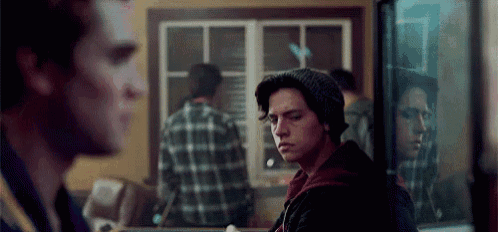 a man is standing in front of a mirror looking at his reflection in the mirror .