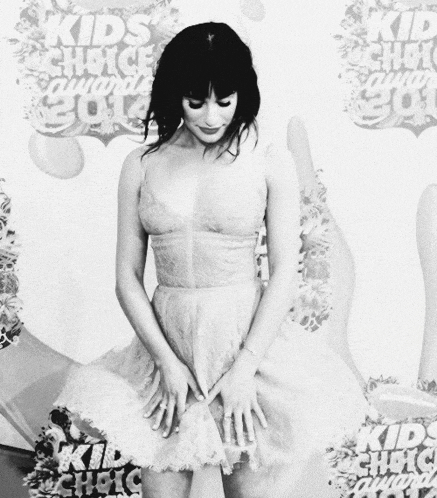 a black and white photo of a woman standing in front of a wall that says kids choice awards 2013