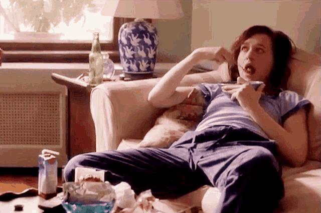 a woman is sitting on a couch with a cup of coffee in her hand