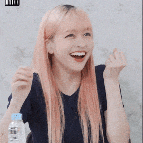 a girl with pink hair is making a heart with her fingers