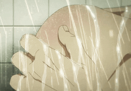 a man is sitting in a corner of a room with a shower head on the wall
