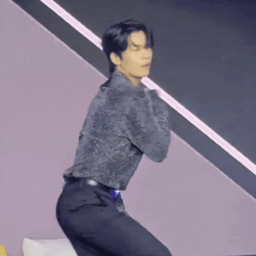 a man in a black shirt and black pants is kneeling down and dancing .