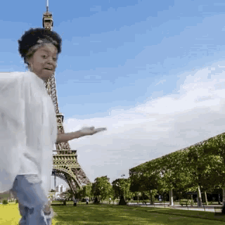 a woman standing in front of the eiffel tower holding something in her hand