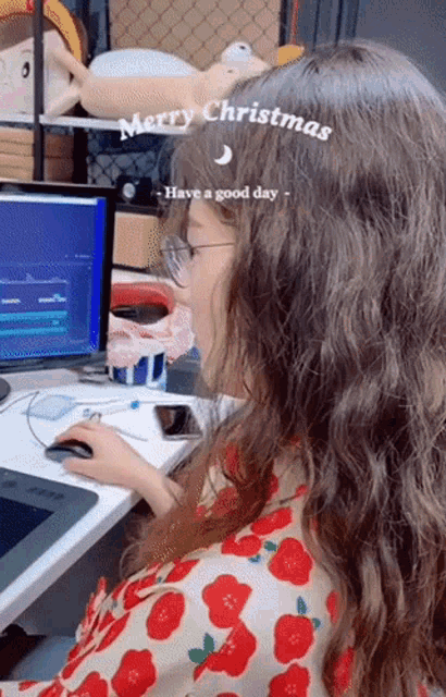 a woman sits at a desk with a computer and the words merry christmas have a good day on her head