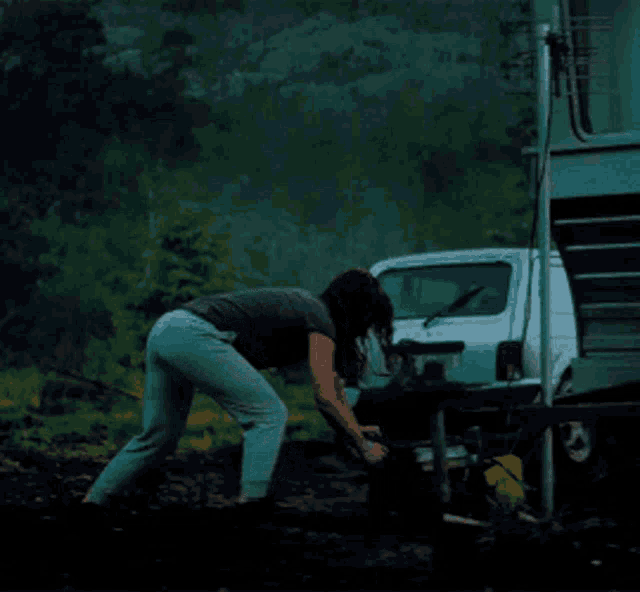 a woman is digging in the dirt next to a white car with a license plate that says ' tk ' on it
