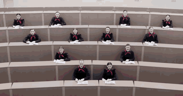 a row of women wearing masks sit at their desks in a classroom