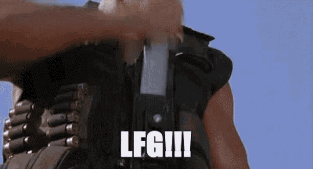 a man wearing a bullet belt is holding a cell phone in his hand and the word leg is on the screen .