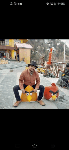 a man in a hat sits on an angry birds statue