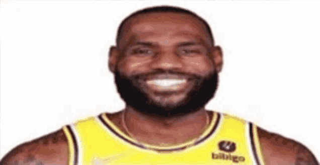 a basketball player with a beard is smiling for the camera while wearing a yellow jersey .