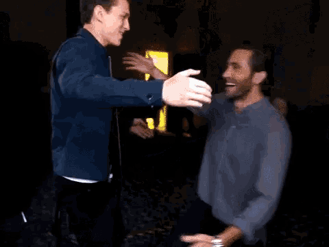 a couple of men are hugging each other in a dark room .