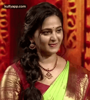 a woman is wearing a green saree and a red blouse .