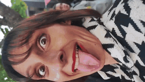 a woman sticking her tongue out while wearing a black and white sweater