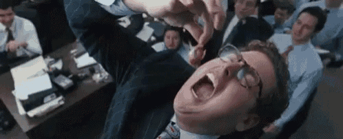a man in a suit and tie is laying on his back with his mouth open in front of a group of men .