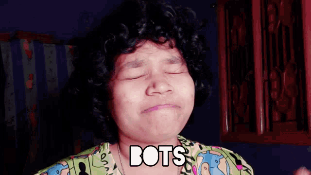 a woman with curly hair is wearing a green shirt that says bots on it