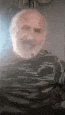 an elderly man with a beard is standing in front of a mirror .