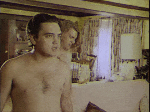 a man without a shirt is standing in front of a woman