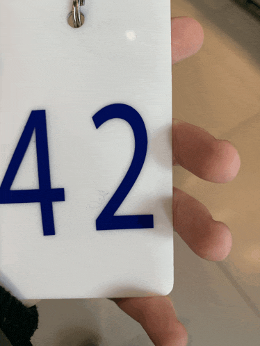 a person is holding a white key chain with the number 42 on it