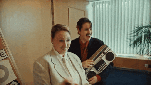 a man and a woman holding a boombox in front of a sign that says ' e '