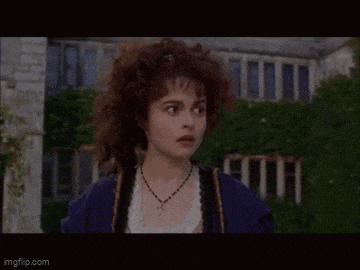 a woman with curly hair is wearing a blue jacket and a necklace .