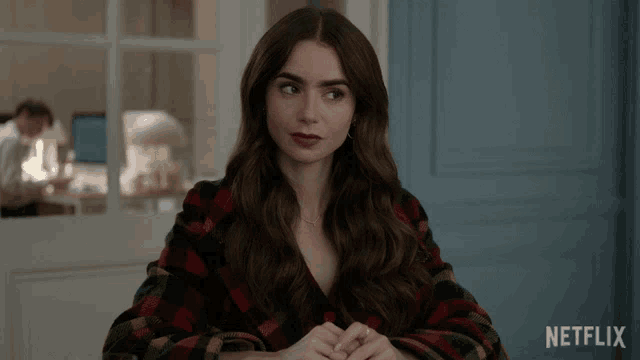 a woman sitting at a table with a netflix logo on the bottom