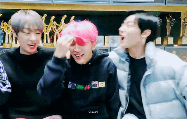 a group of young men are sitting next to each other and one has pink hair