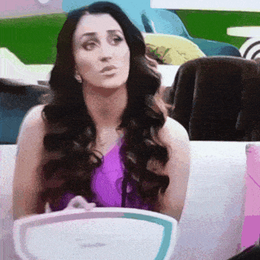 a woman in a purple tank top is sitting on a couch holding a white tray