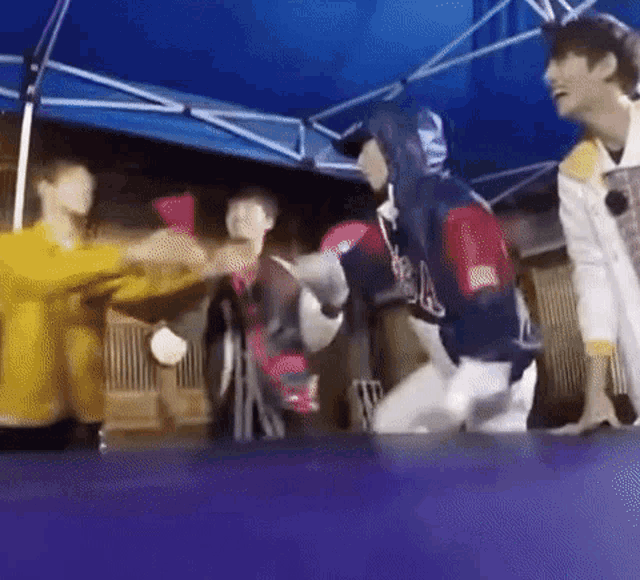 a group of people are standing around a trampoline .
